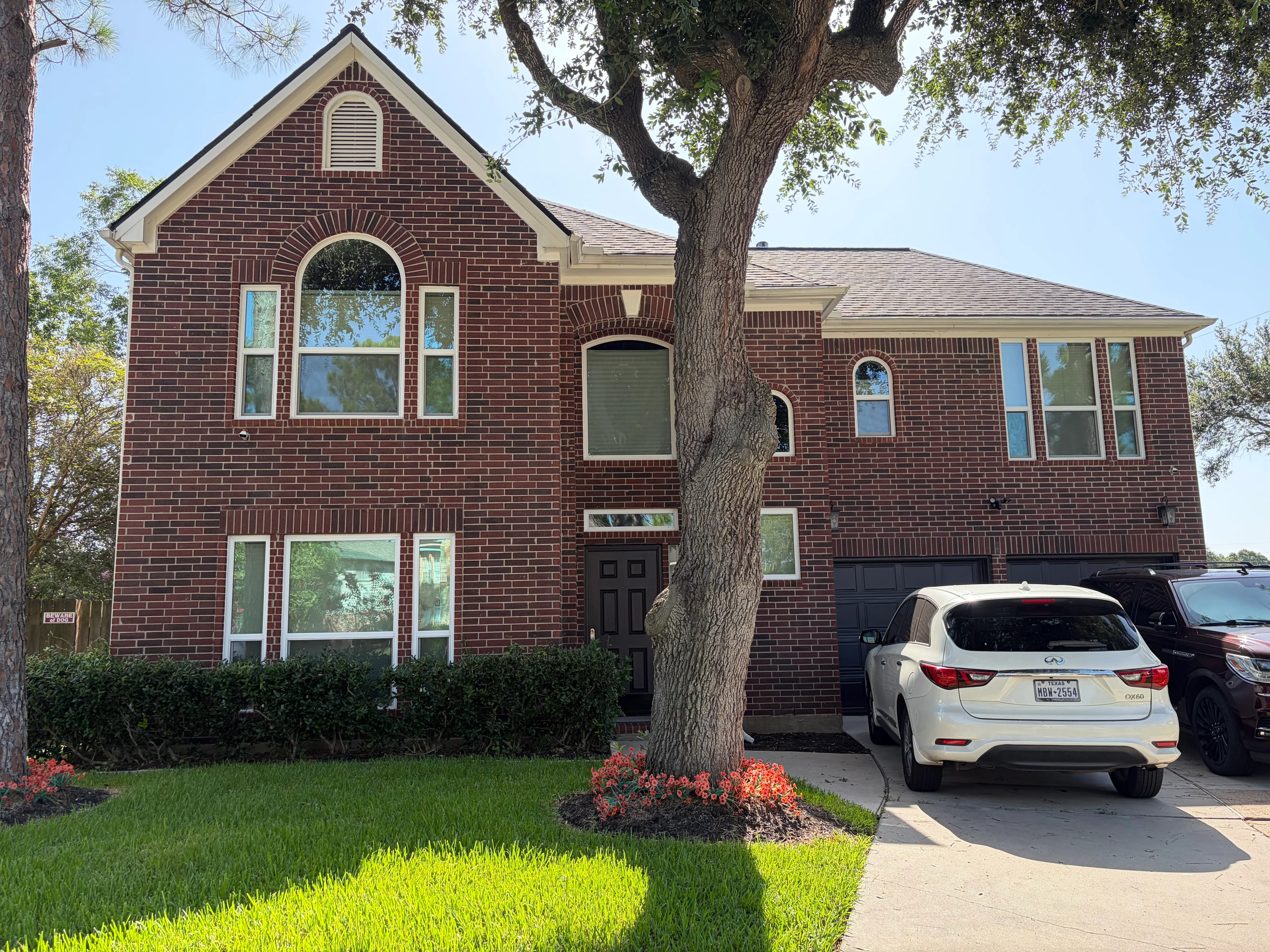 Two-story brick home with newly installed windows including arched and double-hung styles