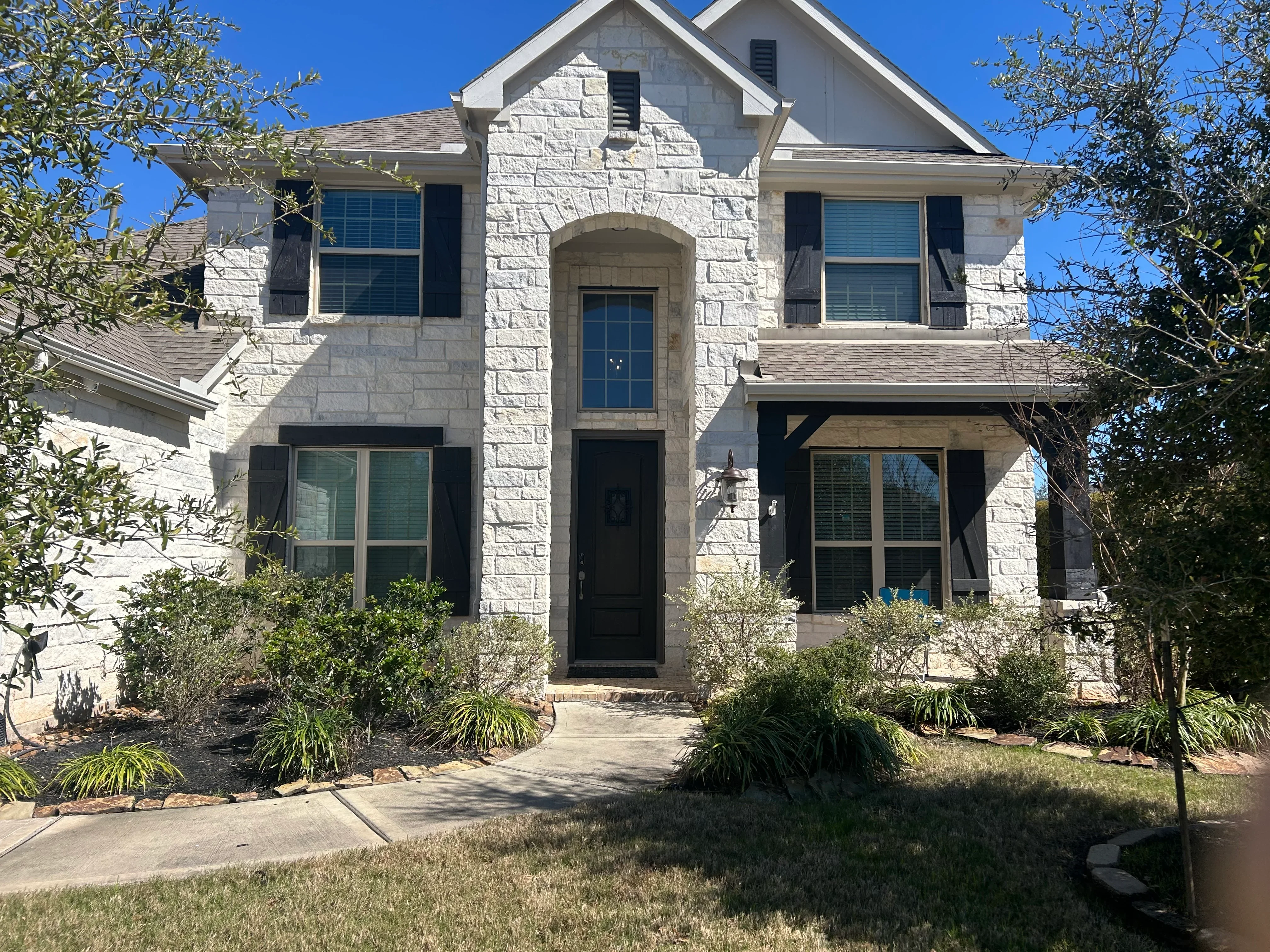 White stone house with new blue-tinted windows and black trim installed across front facade
