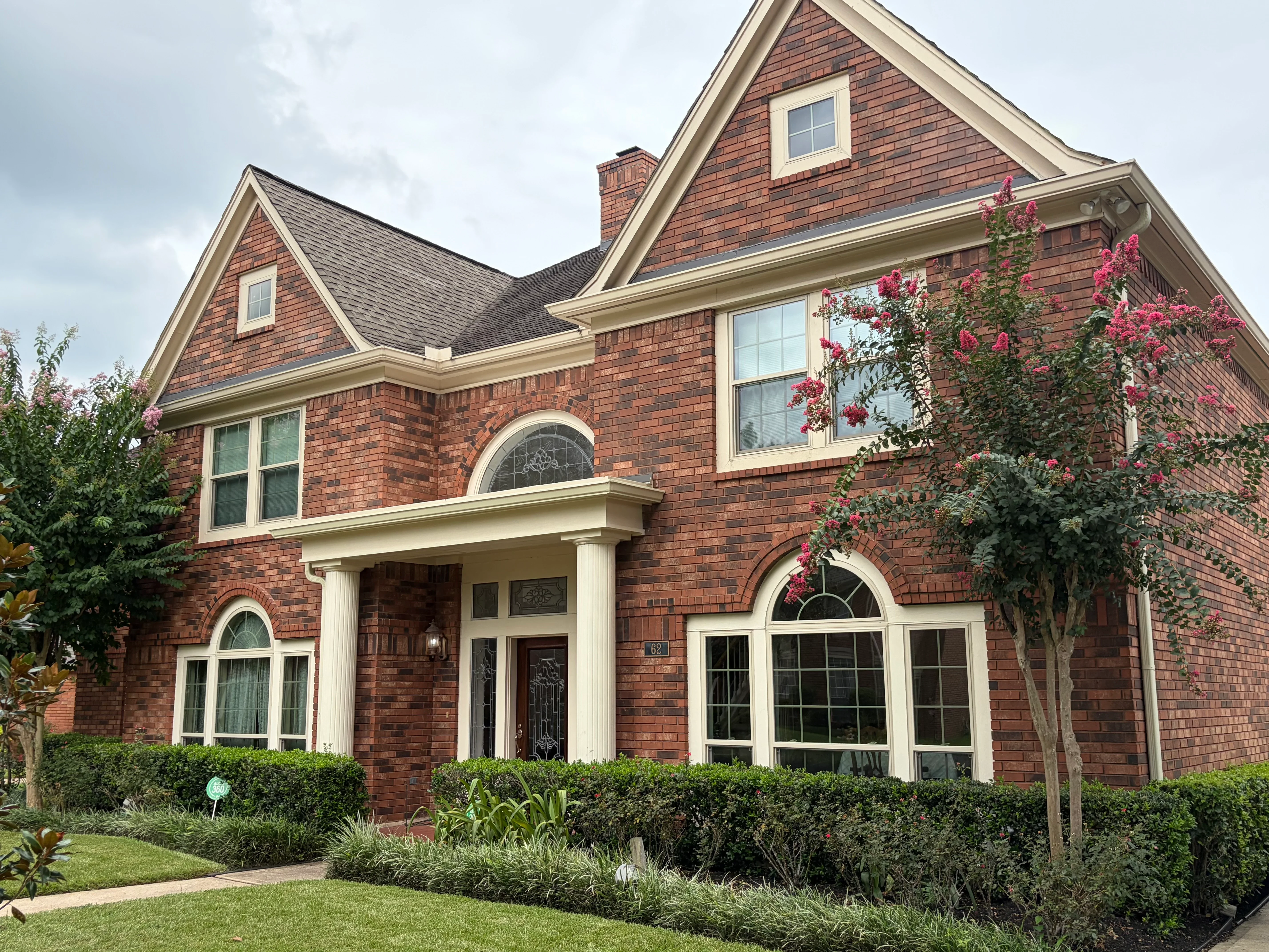 Two-story brick home with new white-trimmed windows, arched transoms, and picture windows installed